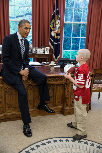 President Barack Obama greets Jack Hoffman, 7, of Atkinson, Neb., in the Oval Office, April 29, 2013. Hoffman, who is battling pediatric brain cancer, gained national attention after he ran for a 69-yard touchdown during a Nebraska Cornhuskers spring football game. Hoffman holds a football that the President signed for him. (Official White House Photo by Pete Souza)